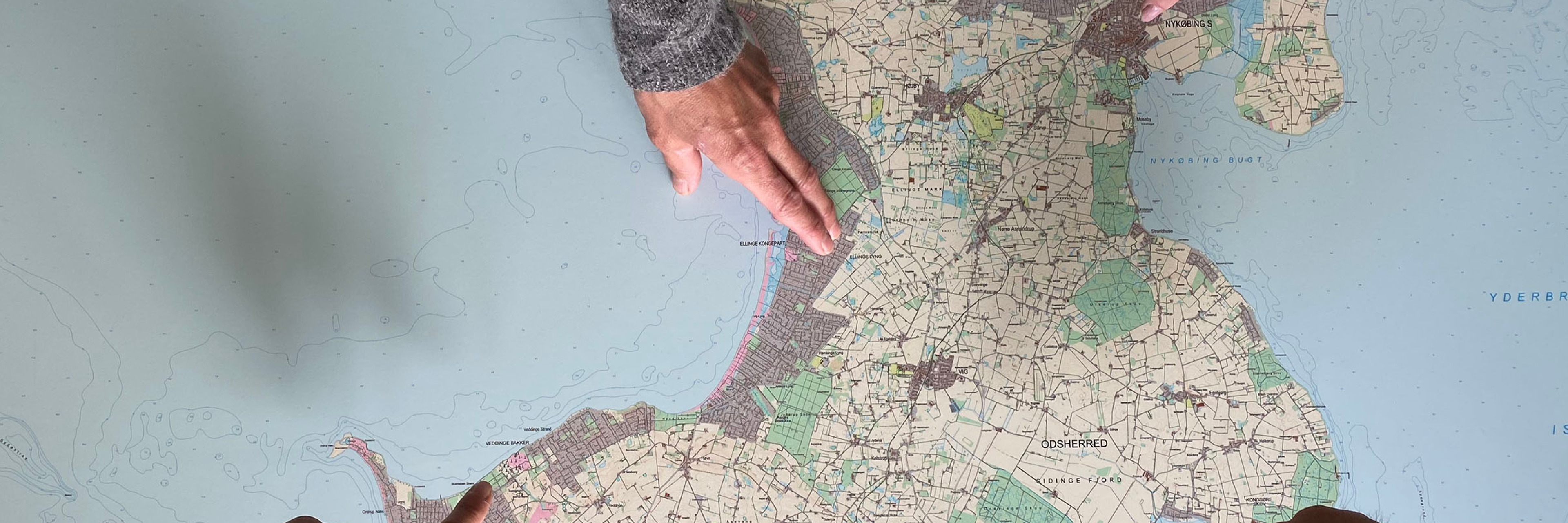 Hænder der peger på et detaljeret landkort over Odsherred