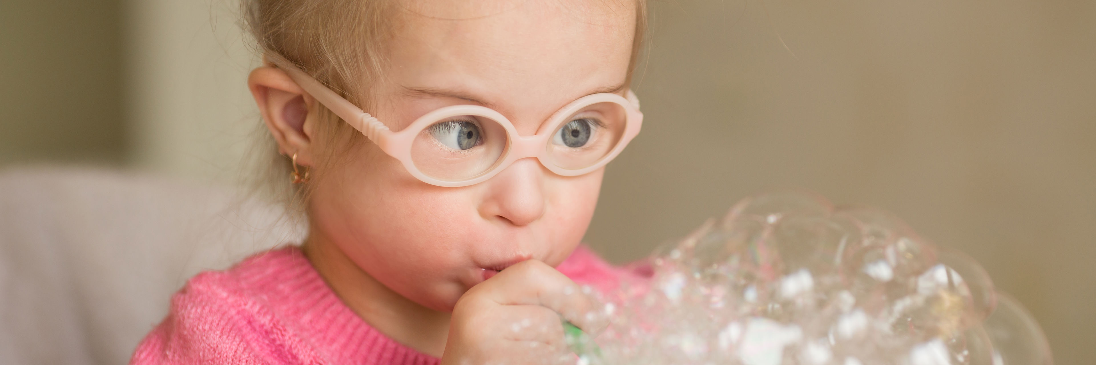 Lille pige der blæser sæbebobler i en glasskål