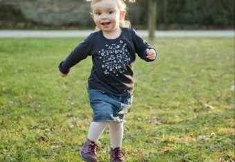 Pige med blå kjole løber på græsset