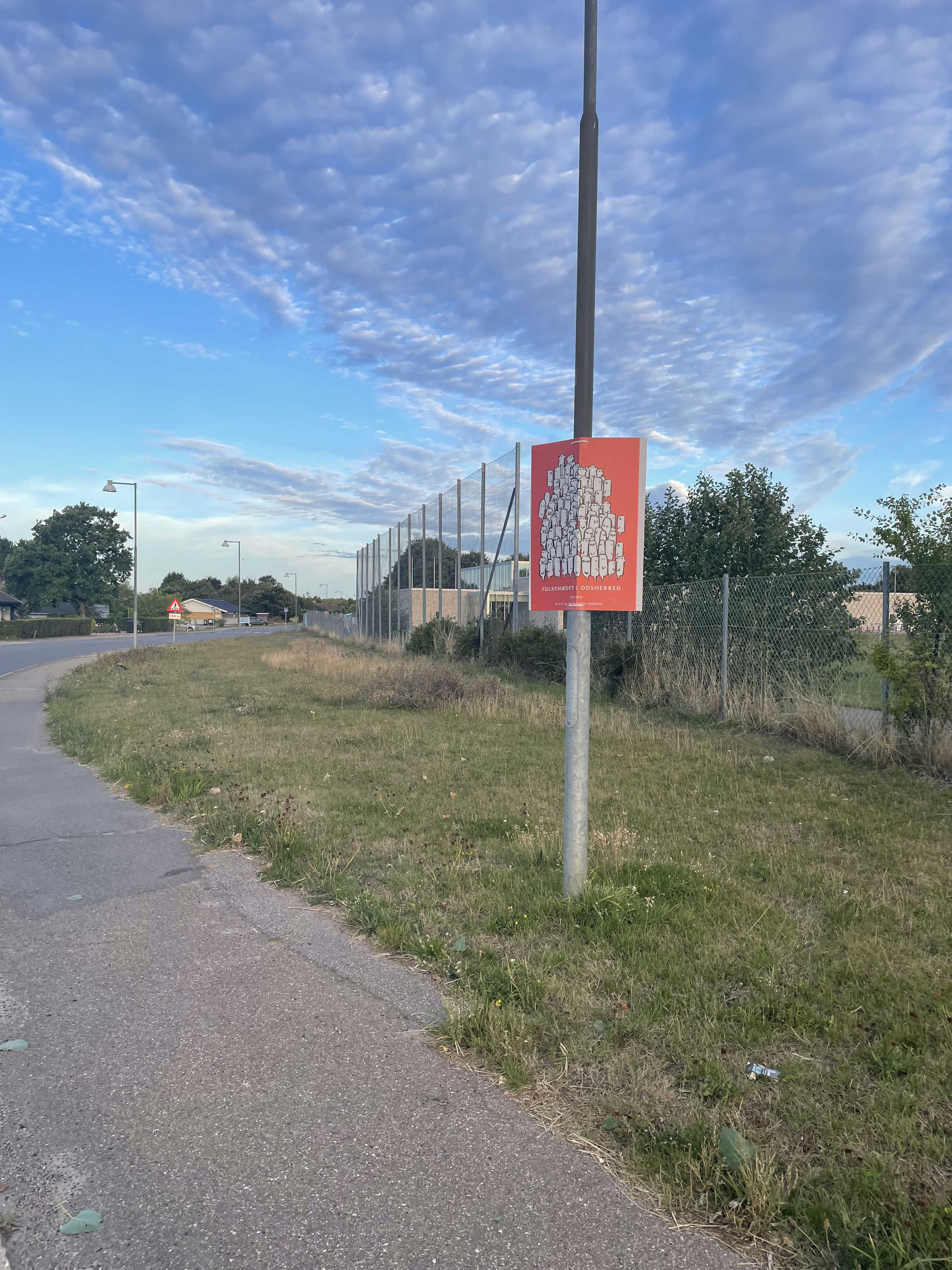 Plakat med reklaem for Folkemødet opsat på lysmast på Nyvej - himen er blå og det er sommer