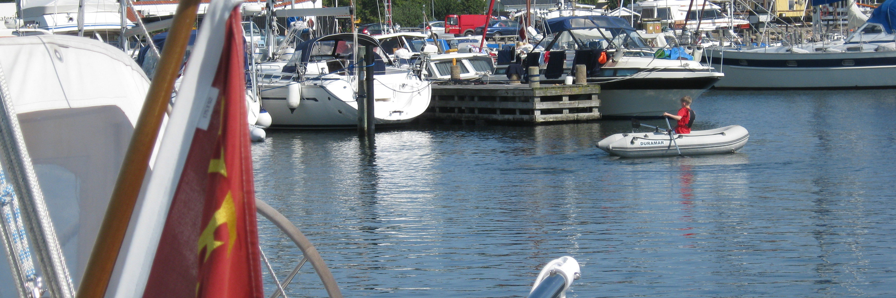 Indsejling til lystbådehavnen. I forgrunden både. I baggrunden huse på havnen.