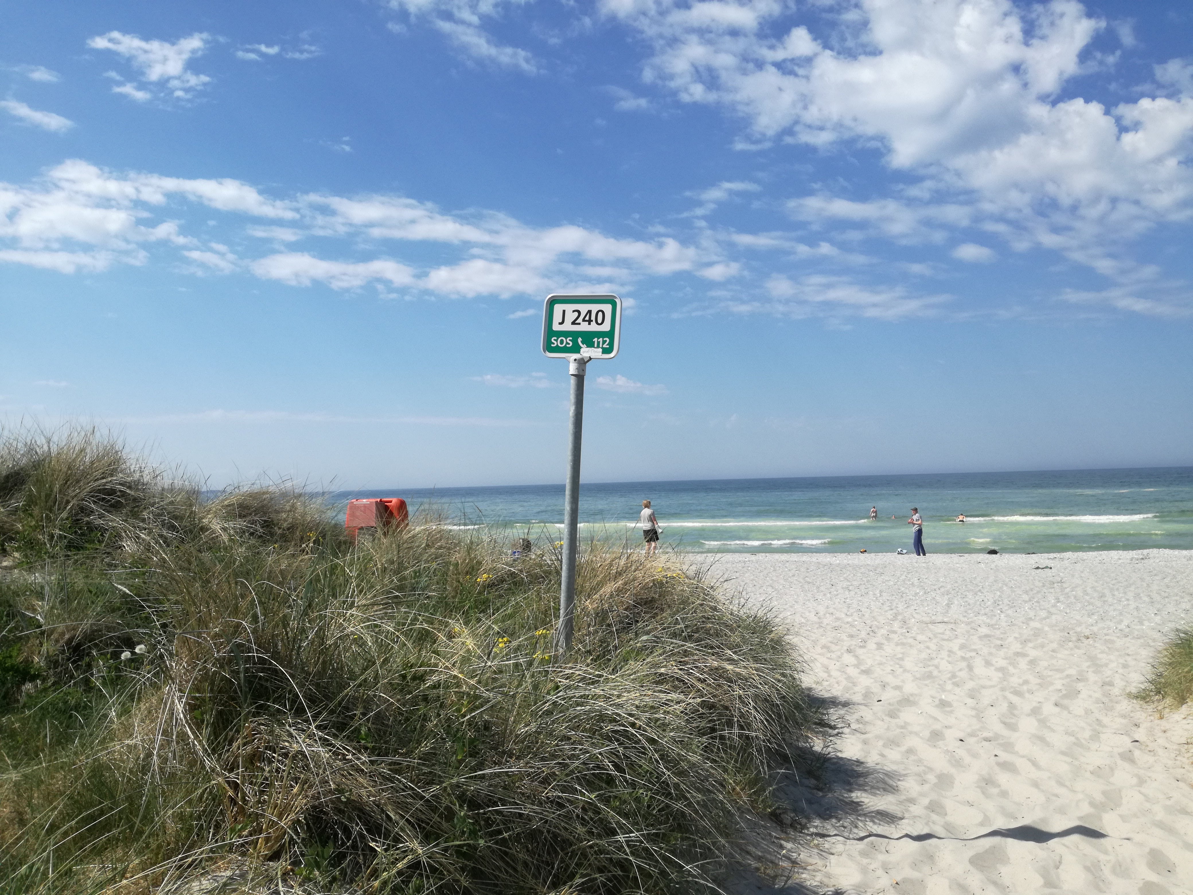 Skilt med redningsnummer på strand