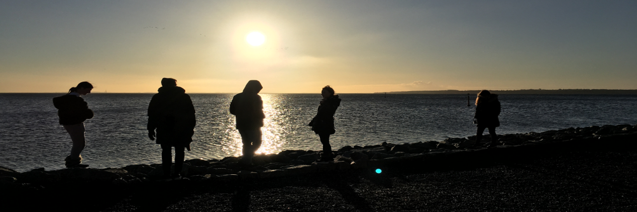 Unge mennesker ved havet ved solopgang