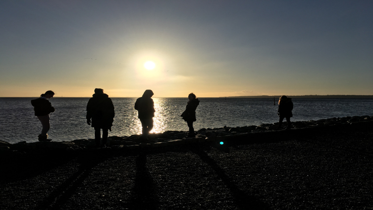 Unge mennesker ved havet ved solopgang