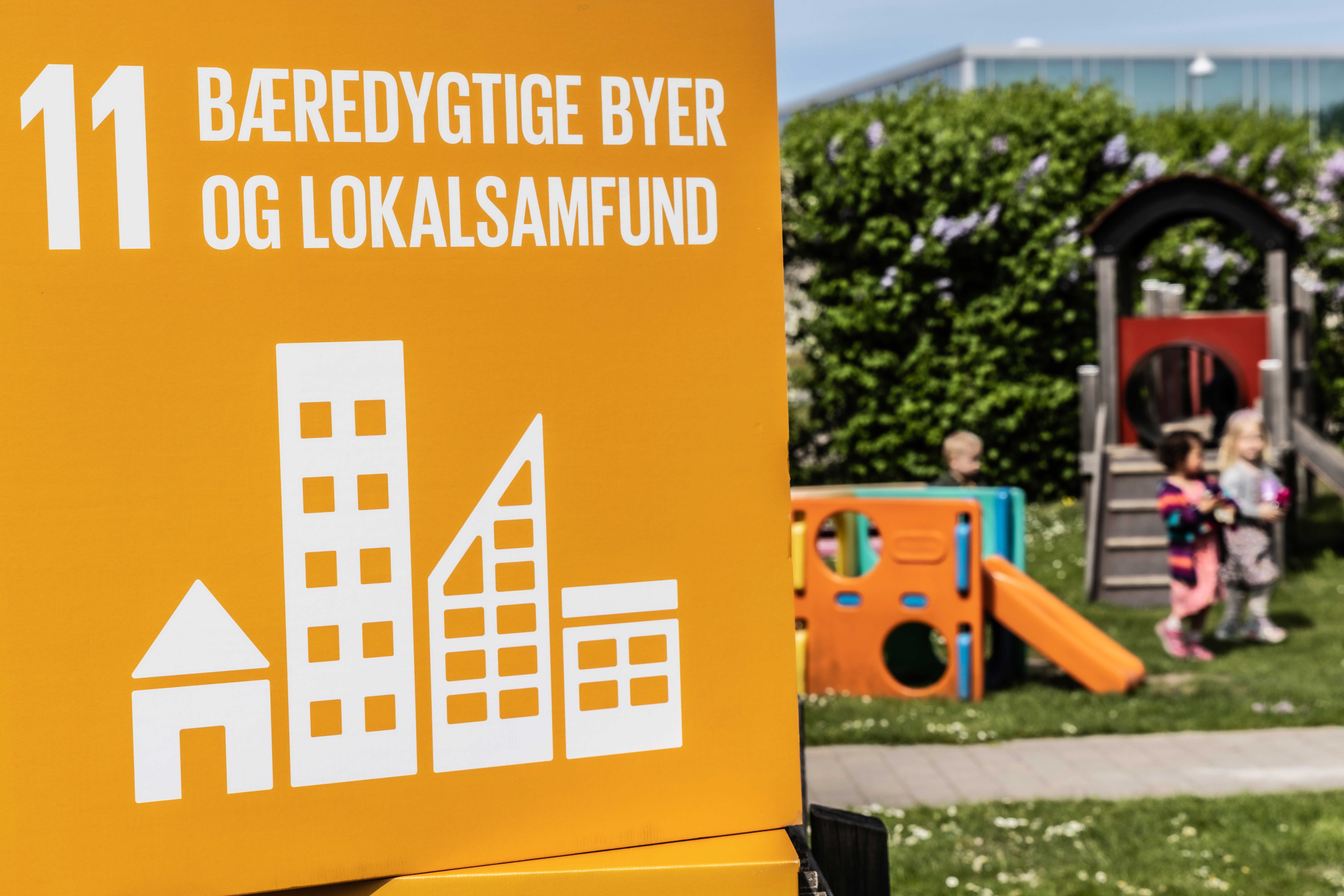 Verdensmål 11: Bæredygtige byer og lokalsamfund. Børn i baggrunden