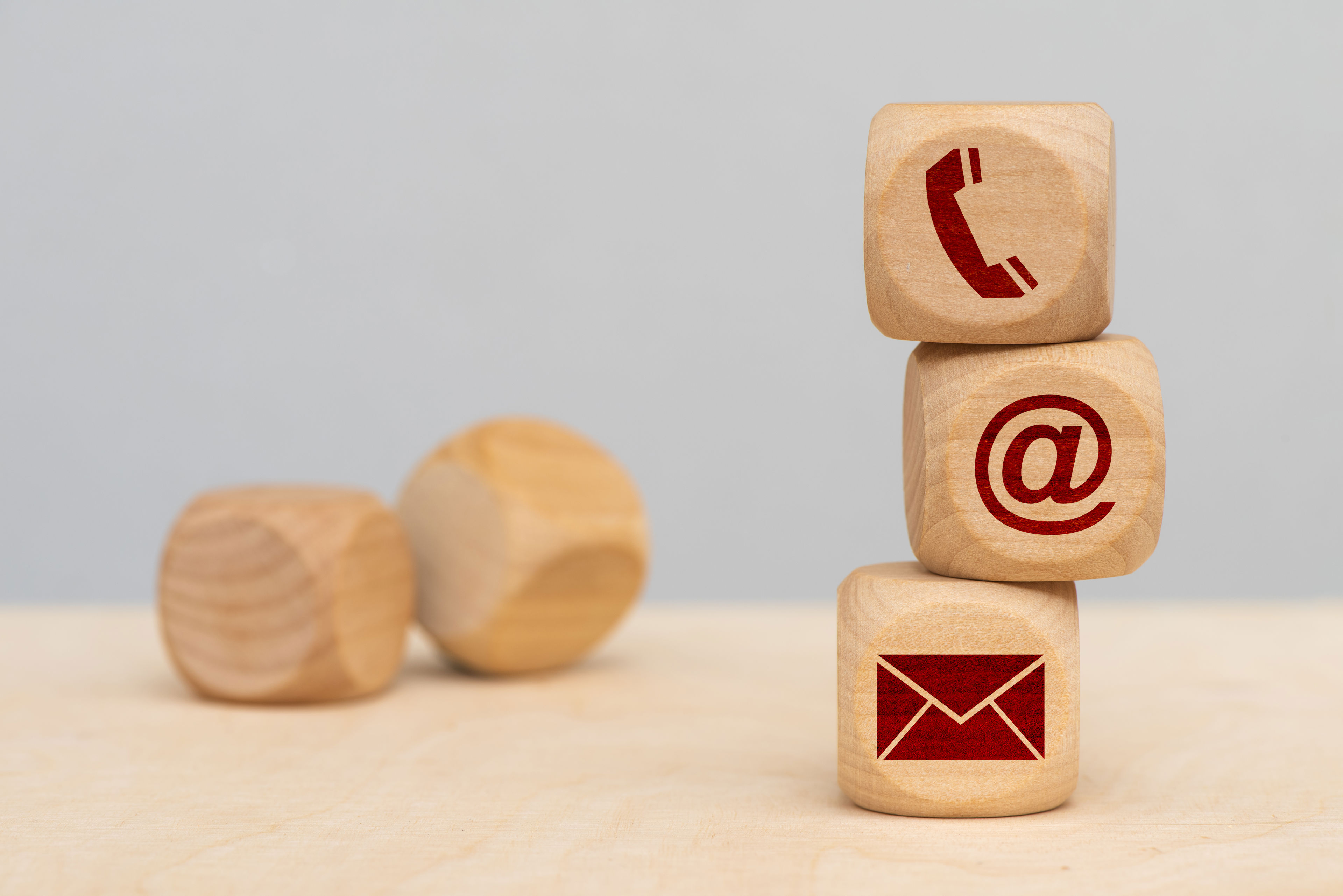 Tre terninger med hhv. en telefon, et snabel-a og en kuvert stablet oven på hinanden