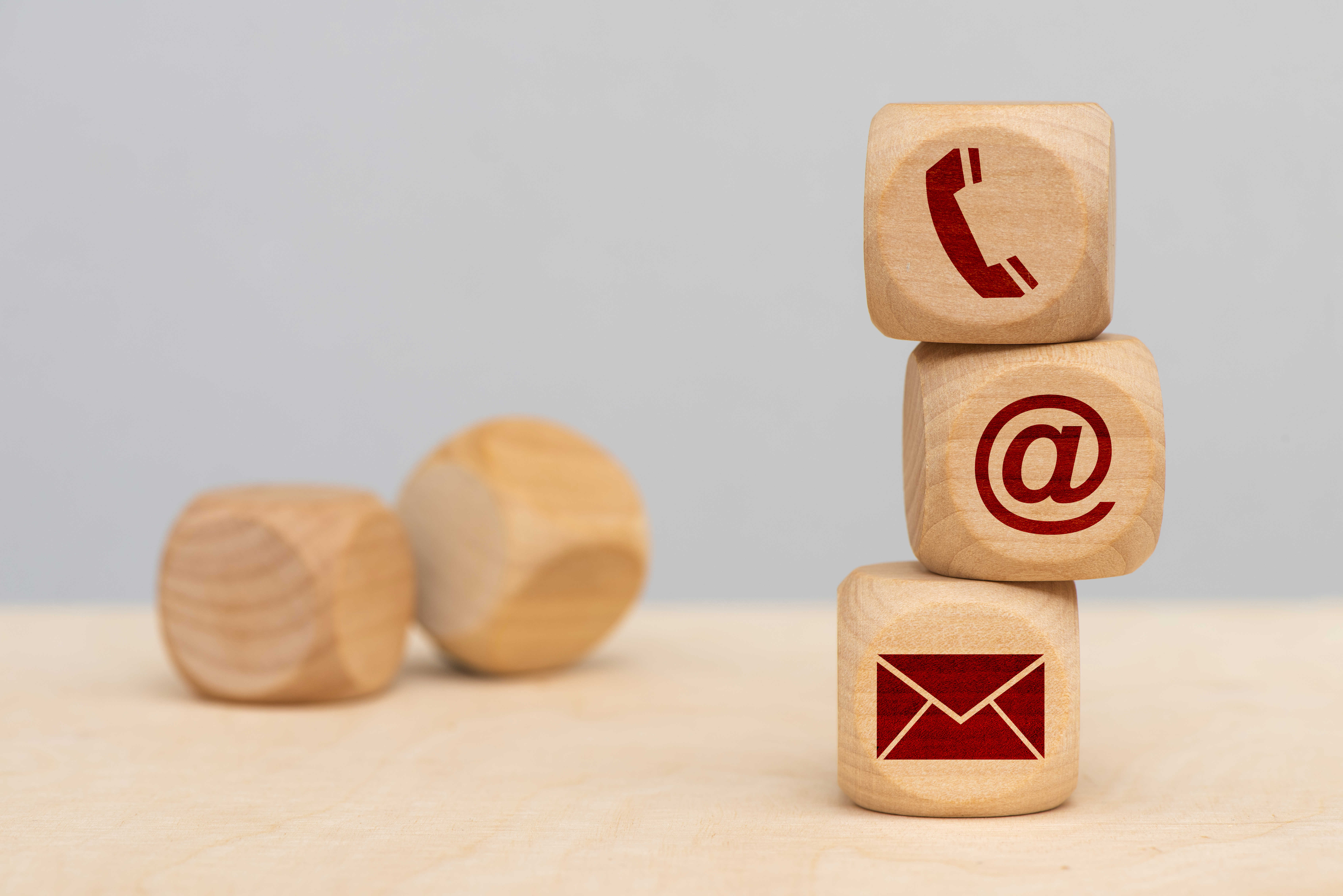 Tre terninger med hhv. en telefon, et snabel-a og en kuvert stablet oven på hinanden