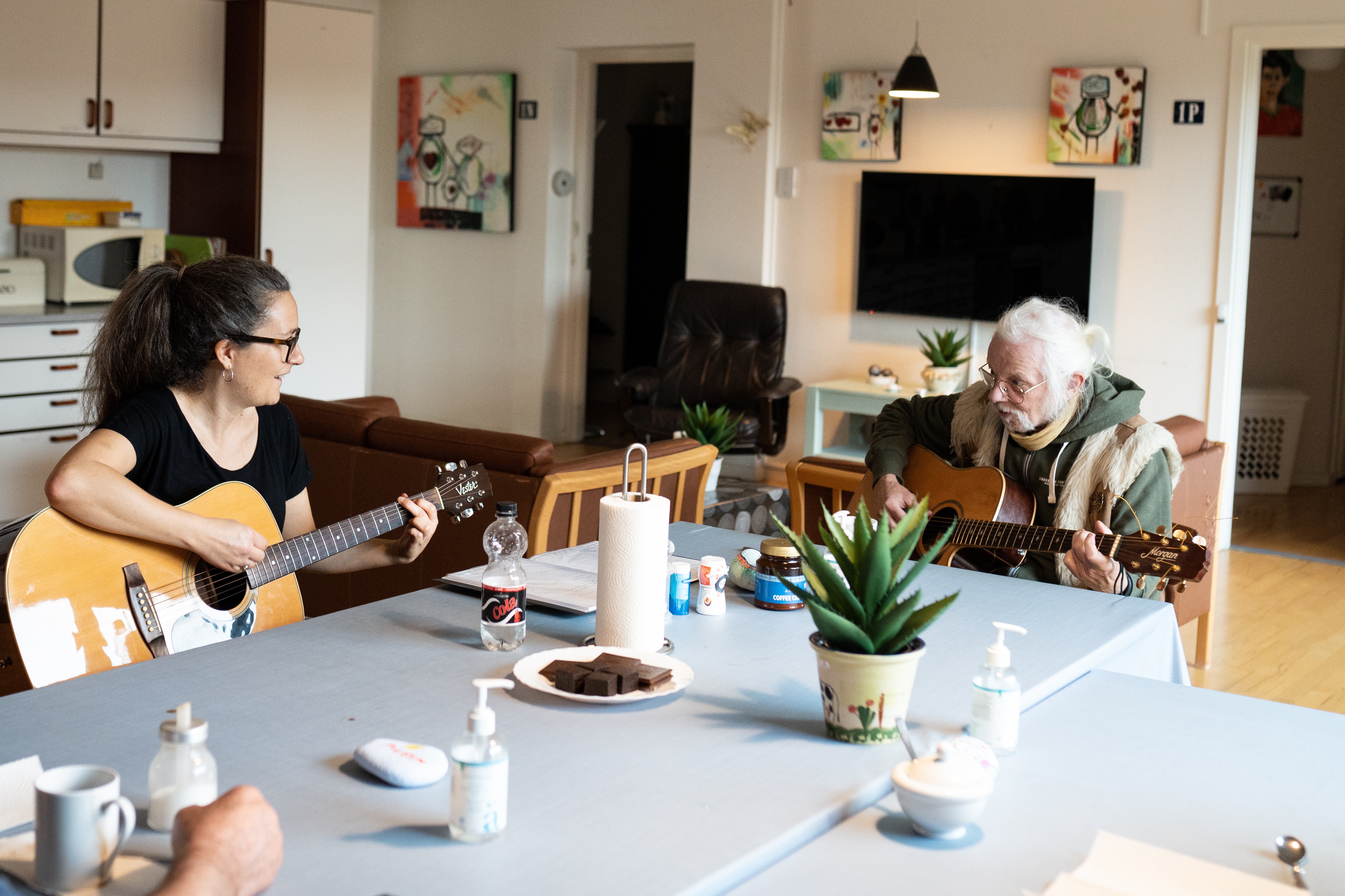 En kvinde og mand sidder og spiller guitar