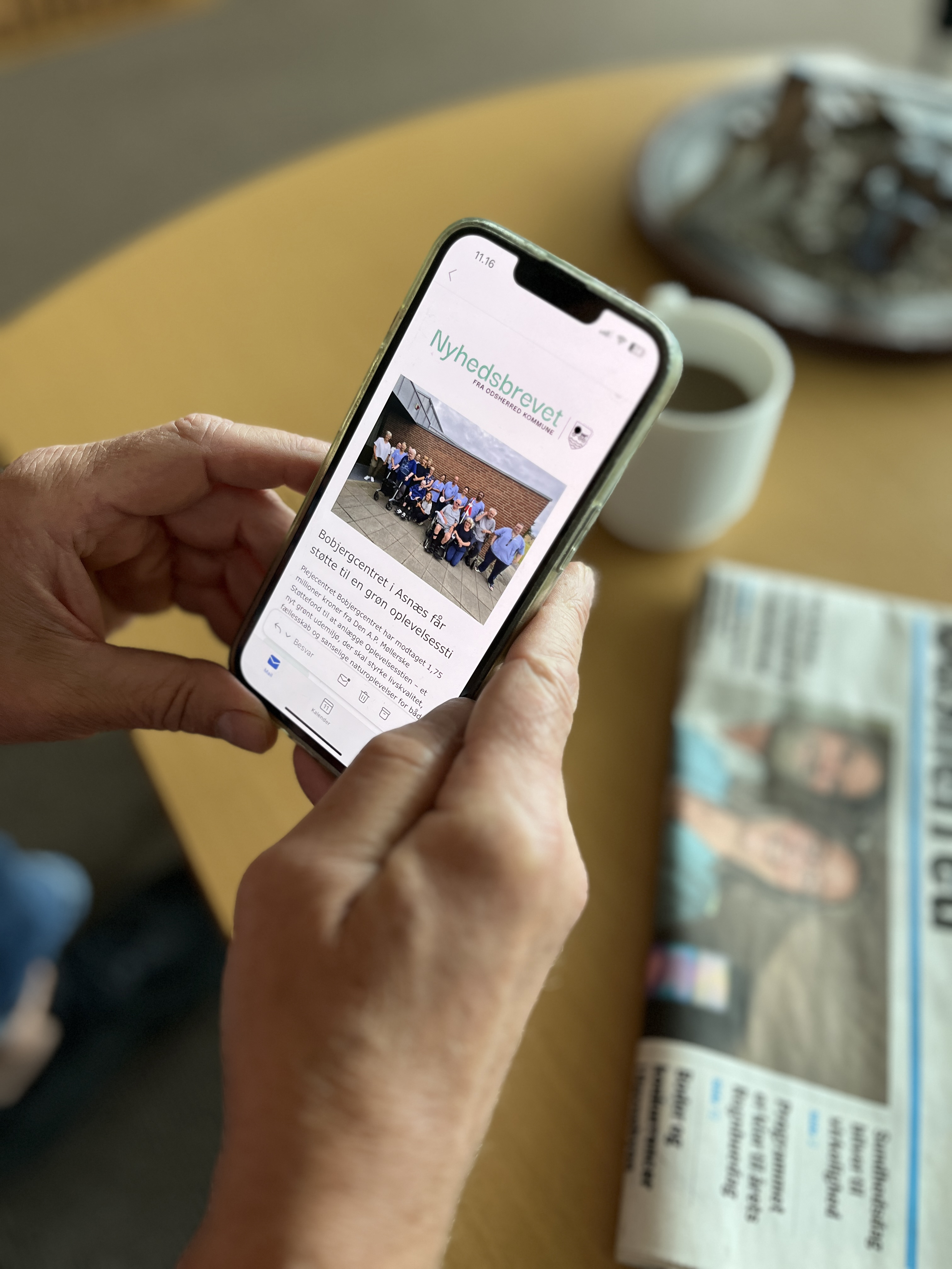 En person læser nyhedsbrevet fra Odsherred Kommune på sin telefon