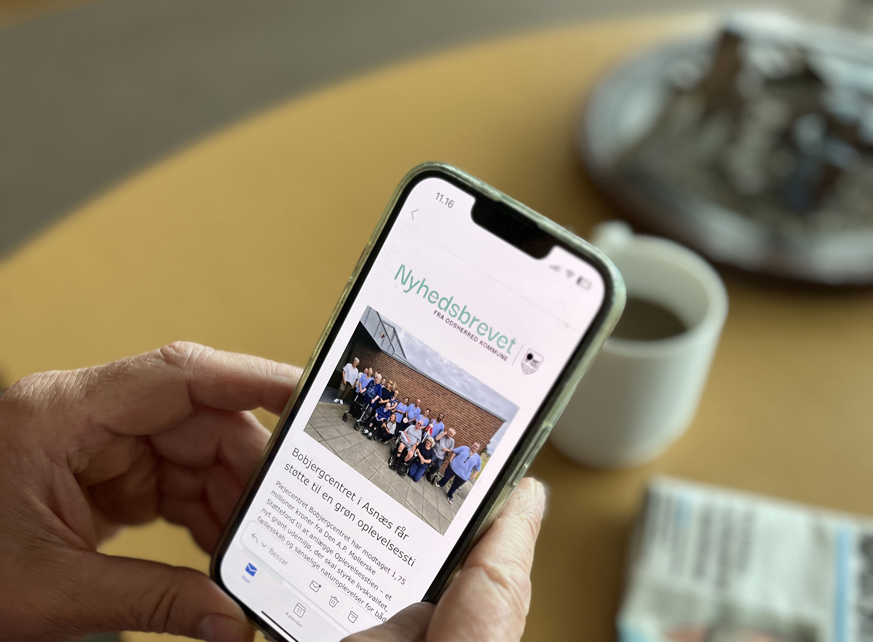 En person læser nyhedsbrevet fra Odsherred Kommune på sin telefon