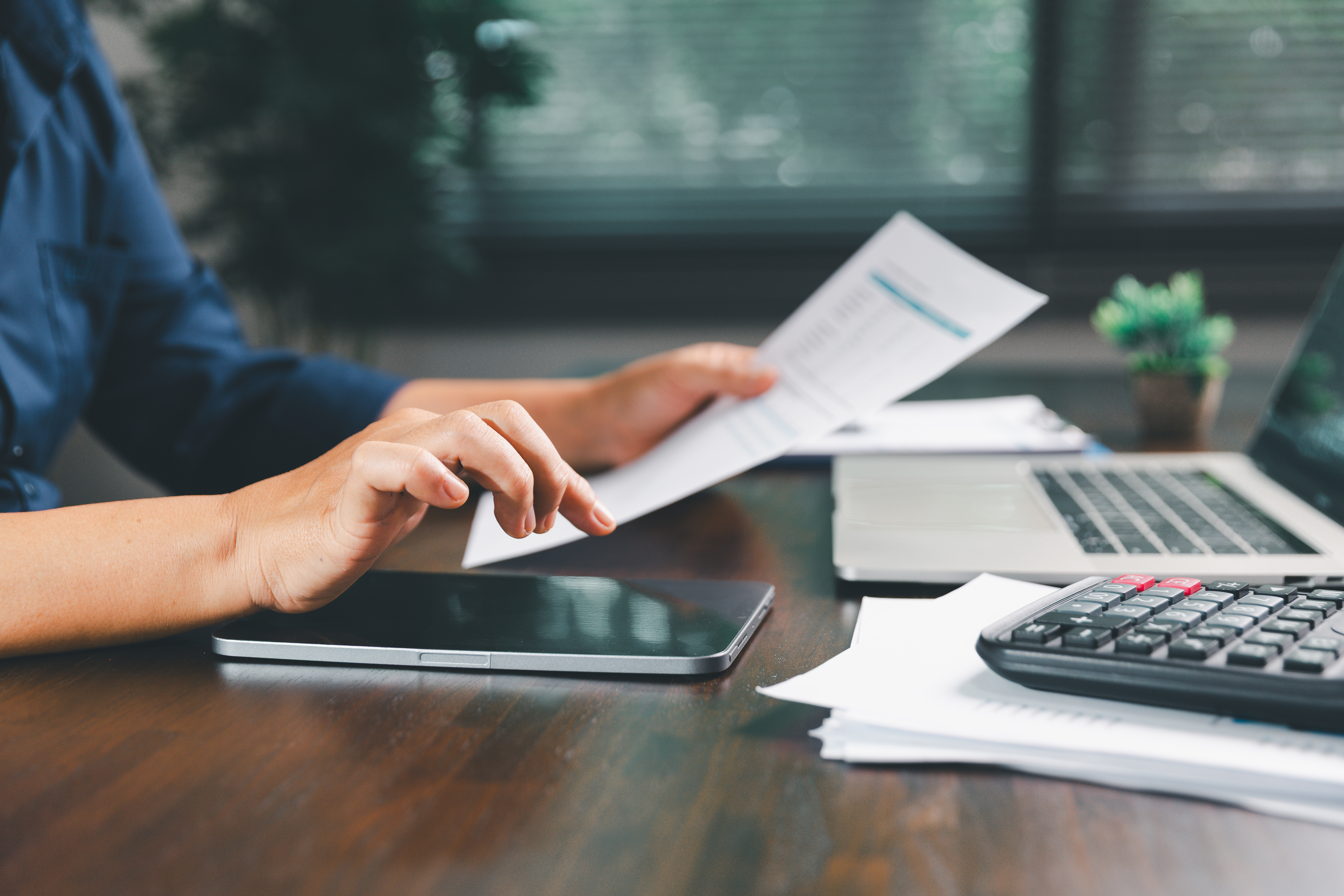 Person ved skrivebord med papirer og lommeregner
