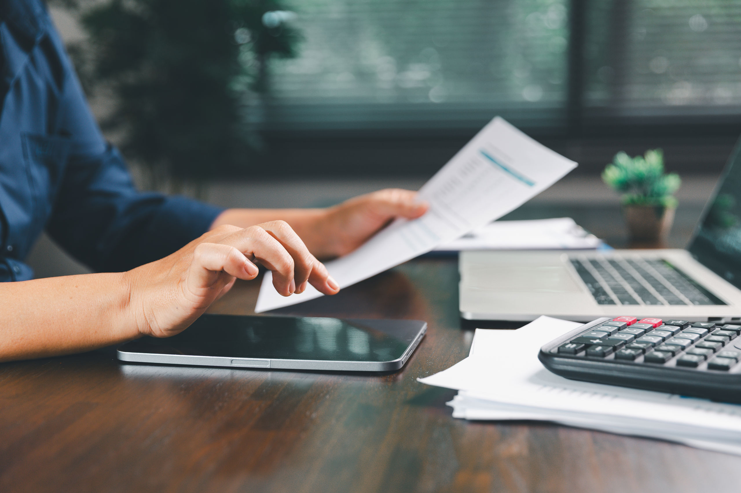 Person ved skrivebord med papirer og lommeregner