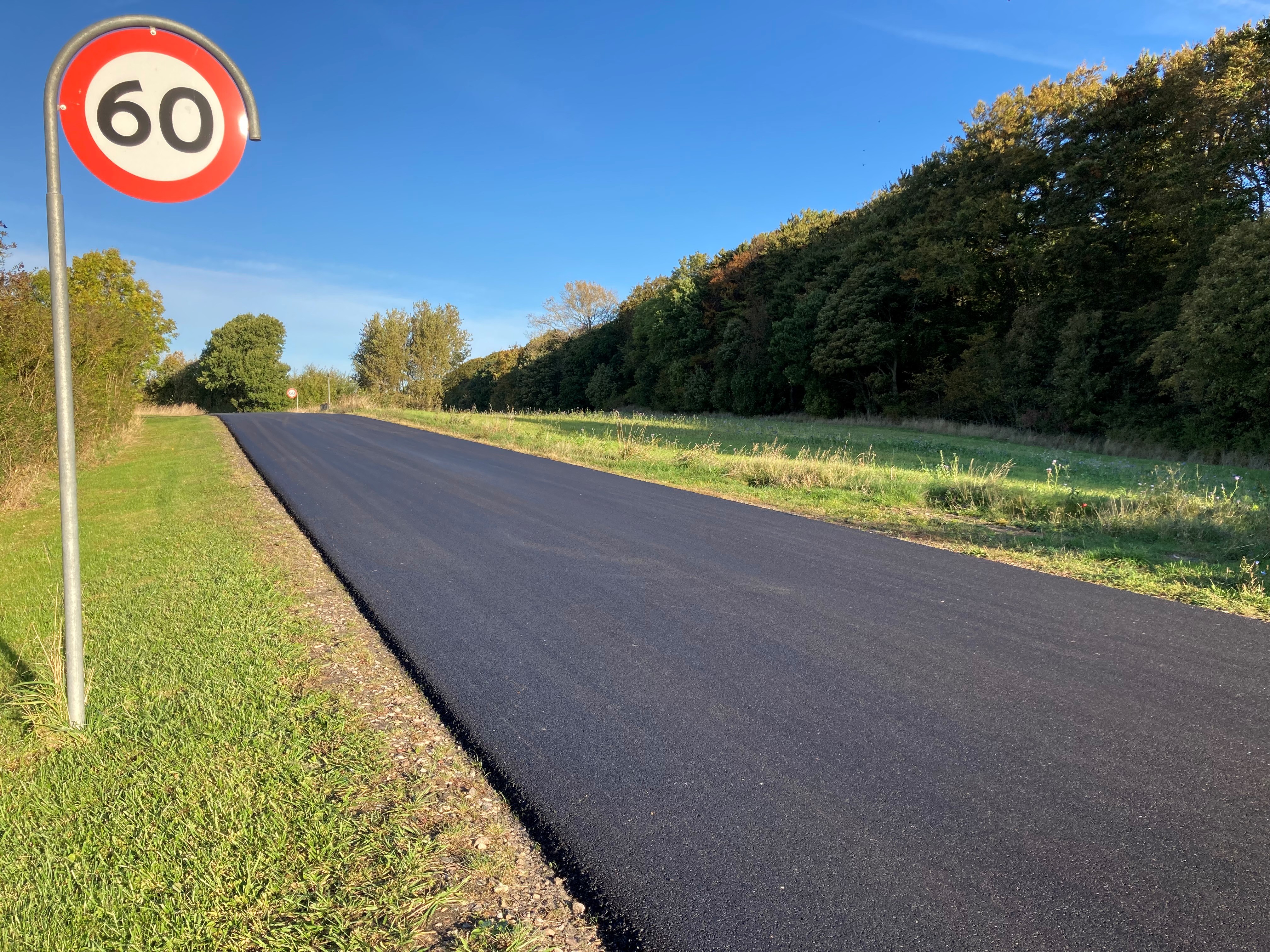 Nyasfalteret vej, stadig uden striber, ved nyklippede græsrabatter